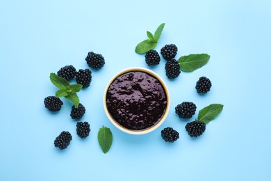 Blackberry puree in bowl and fresh berries with mint on light blue background, flat lay