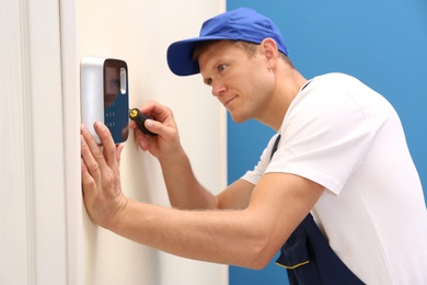 Male technician installing security alarm system indoors