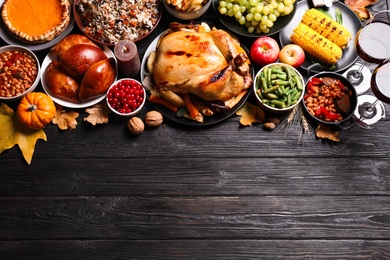 Traditional Thanksgiving day feast with delicious cooked turkey and other seasonal dishes on black wooden table, flat lay. Space for text