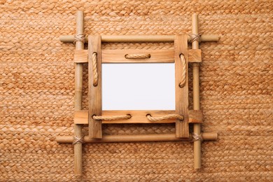 Empty bamboo frame on wicker straw background, top view. Space for text