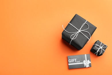 Gift card and presents on orange background, flat lay. Space for text