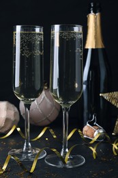 Happy New Year! Glasses of sparkling wine and festive decor on black background