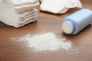 Photo of Bottle, scattered dusting powder and diapers on wooden background. Baby care products