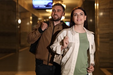 Photo of Happy couple with backpacks on subway station. Public transport