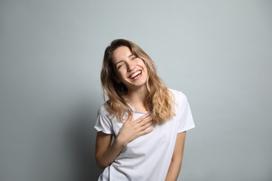 Photo of Cheerful young woman laughing on grey background