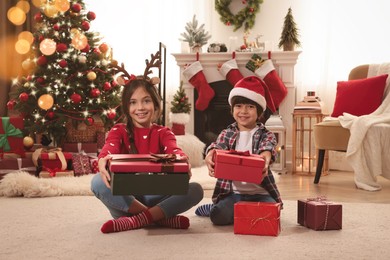 Happy children with Christmas gifts on floor at home