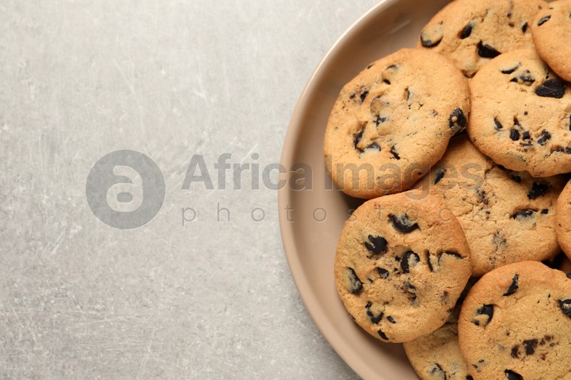 Plate with delicious chocolate chip cookies on grey table, top view. Space for text