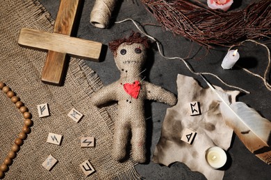 Voodoo doll pierced with pins and ceremonial items on grey table, flat lay