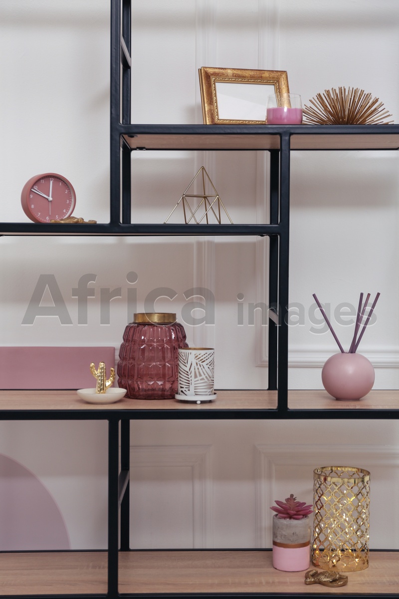 Photo of Stylish shelving unit with different decor near white wall indoors. Interior design