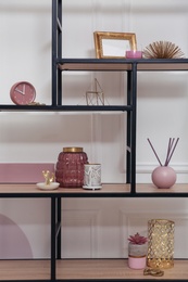 Stylish shelving unit with different decor near white wall indoors. Interior design