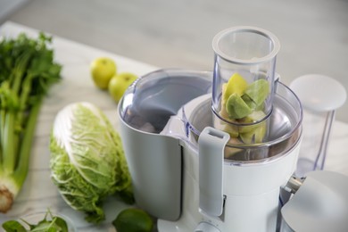 Photo of Modern juicer with fresh fruits on table in kitchen, closeup