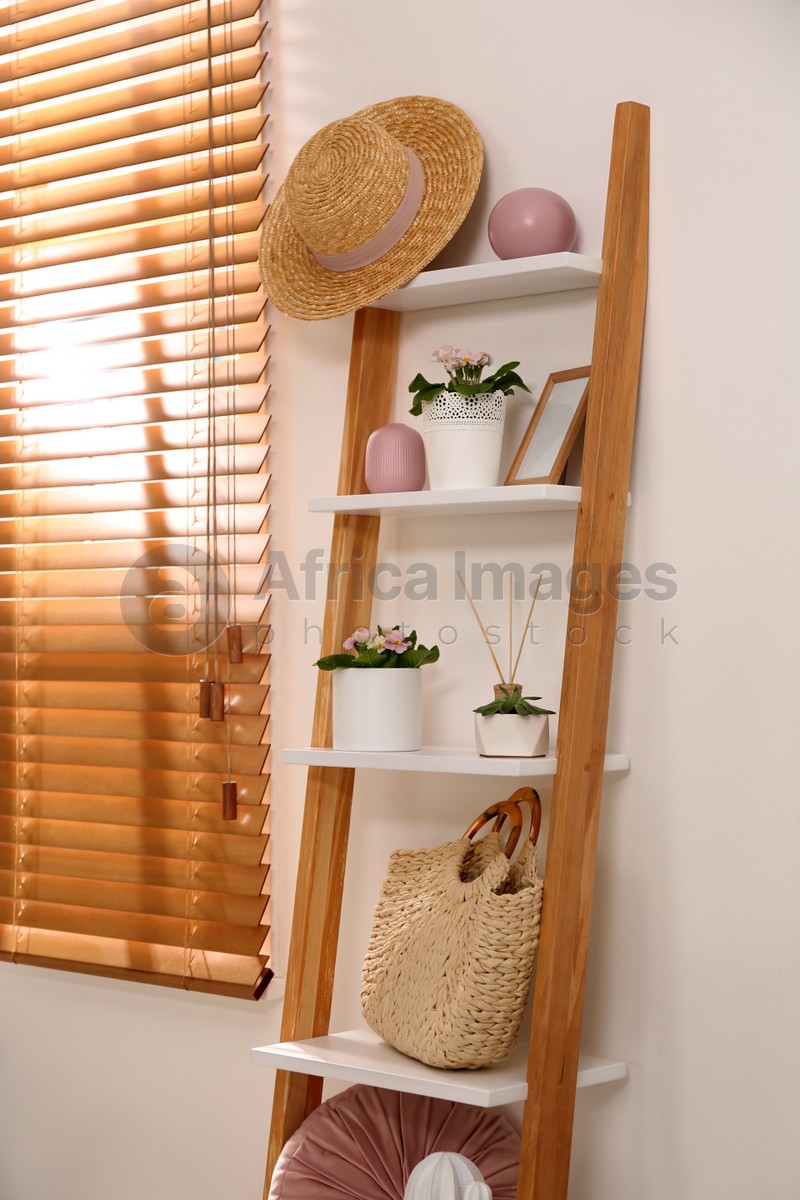 Photo of Stylish room interior with wooden ladder near white wall