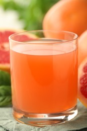 Glass of delicious grapefruit juice on table, closeup