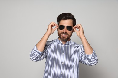 Portrait of smiling bearded man with sunglasses on grey background