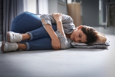 Lonely depressed woman lying on floor at home