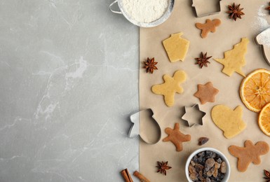 Flat lay composition with unbaked cookies and cutters on light grey marble table, space for text. Christmas biscuits
