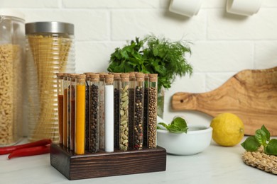 Glass tubes with different spices on kitchen counter