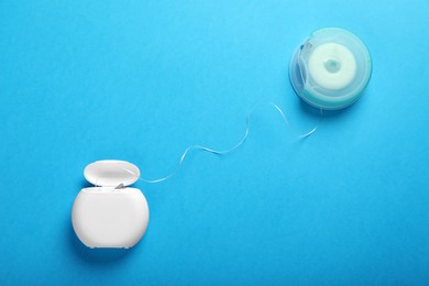 Photo of Containers with dental floss on light blue background, flat lay. Mouth hygiene