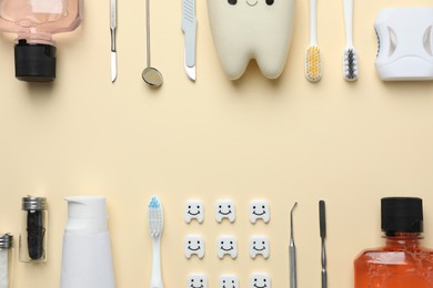 Plastic teeth with cute faces, oral care products and dental tools on beige background, flat lay. Space for text