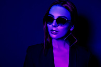 Image of Beautiful woman wearing jacket and sunglasses in neon lights