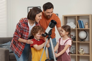 Photo of Happy family looking at stars through telescope in room