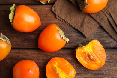 Delicious fresh persimmons on brown wooden table, flat lay