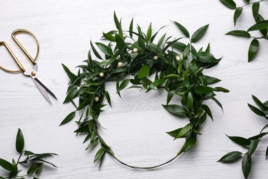 Unfinished mistletoe wreath and florist supplies on white wooden table, flat lay. Traditional Christmas decor