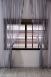 Window with beautiful curtains and blinds in empty room
