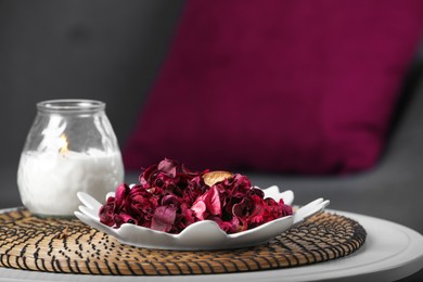 Photo of Aromatic potpourri of dried flowers and burning candle on table indoors