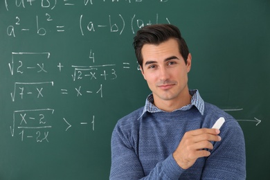Young teacher near chalkboard with math formulas