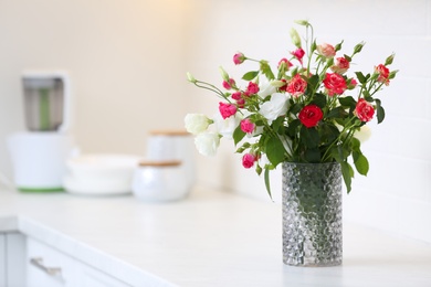 Vase with beautiful flowers on white countertop in kitchen, space for text