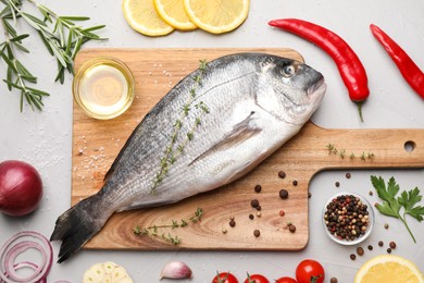 Flat lay composition with fresh raw dorado fish and ingredients on light grey table