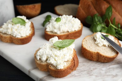 Photo of Bread with cottage cheese and basil on board, closeup