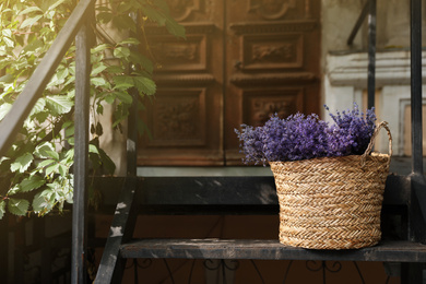 Wicker basket with beautiful lavender flowers on metal stairs near building