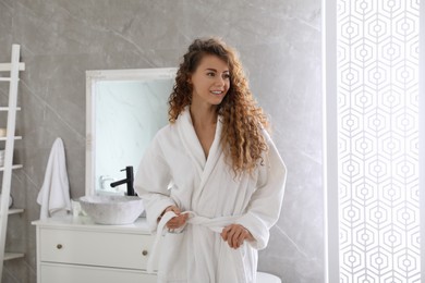 Beautiful woman wearing soft white robe in bathroom