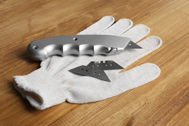 Utility knife, blades and glove on wooden table