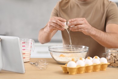 Man making dough while watching online cooking course via tablet in kitchen, closeup