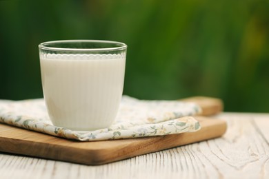 Glass of tasty fresh milk on white wooden table, closeup. Space for text