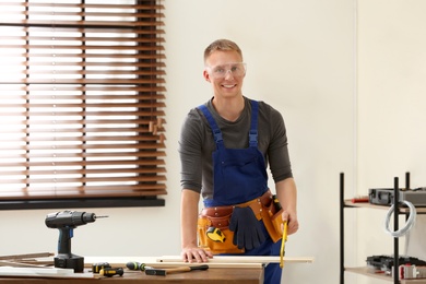 Handsome young working man using hand saw indoors. Home repair
