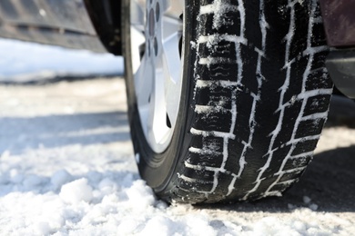 Car with winter tires on snowy road, closeup view