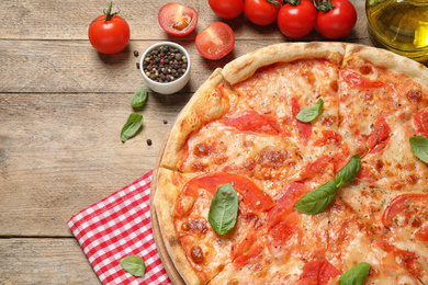 Photo of Delicious pizza Margherita and ingredients on wooden table, flat lay