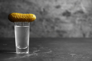 Cold Russian vodka with pickle on black table. Space for text