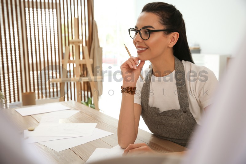 Young woman drawing with pencil at table indoors. Space for text