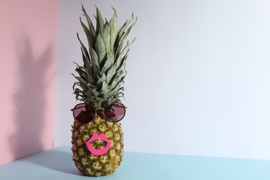 Photo of Pineapple with sunglasses and paper lips on color background, space for text. Creative concept