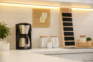 Modern coffeemaker on countertop near brick wall in kitchen
