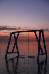 Picturesque view of swing in water on sunrise