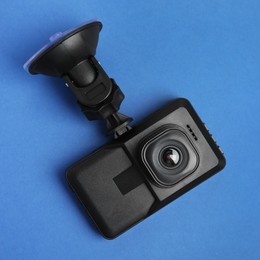 Modern car dashboard camera with suction mount on blue background, top view