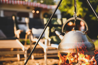 Teapot heating on open fire outdoors. Camping season