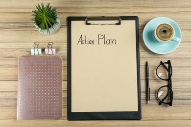 Flat lay composition of clipboard with action plan on wooden table