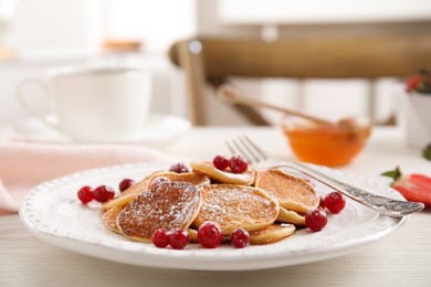 Delicious mini pancakes cereal with cranberries served on white wooden table